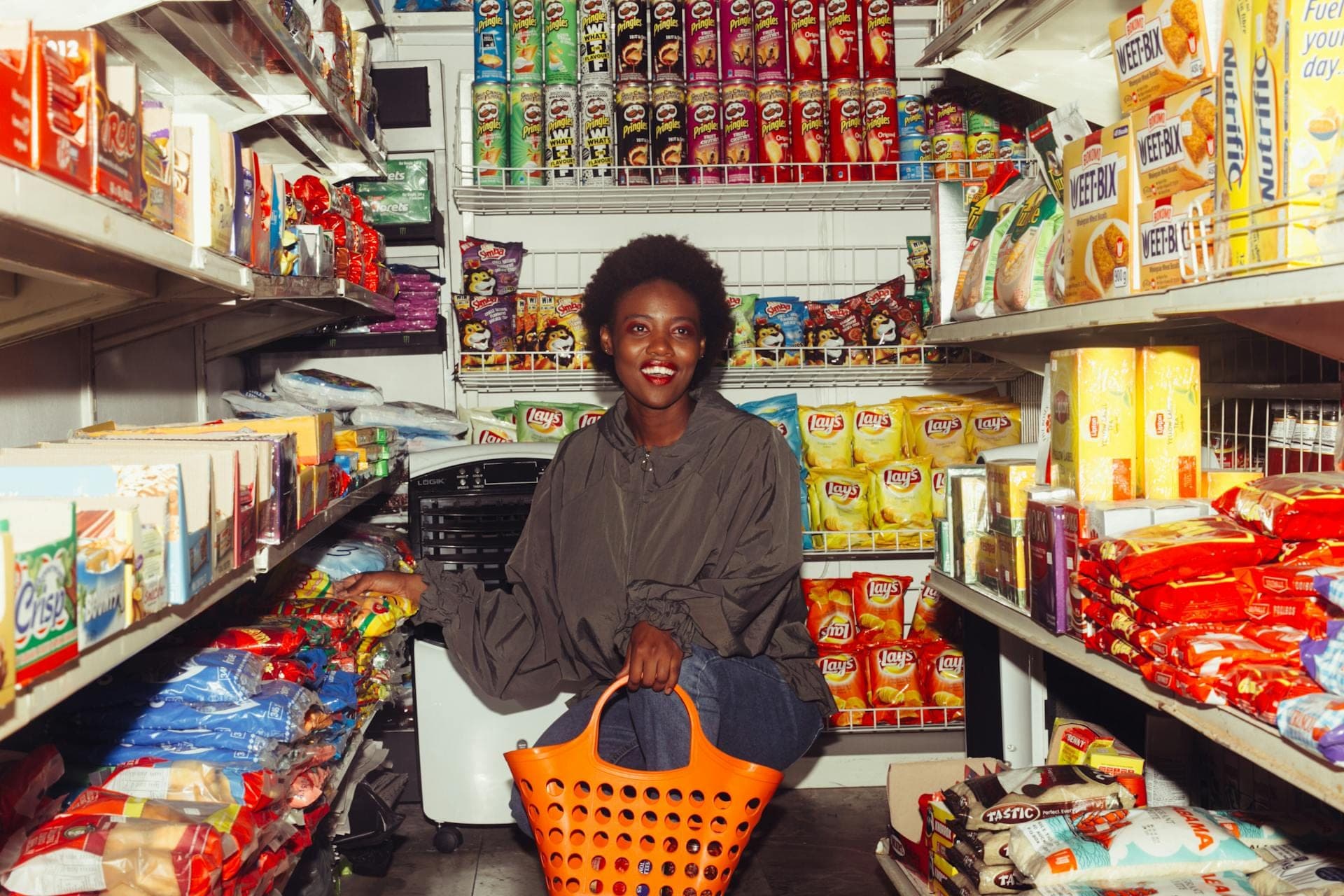 Shopper with an orange basket in a supermarket aisle, the photo behind the brand artwork